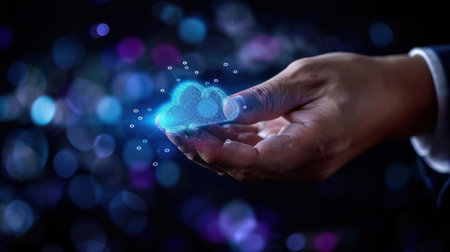A creative representation of cloud technology, featuring a hand holding a glowing digital cloud symbol amidst an abstract background of light and color.の素材