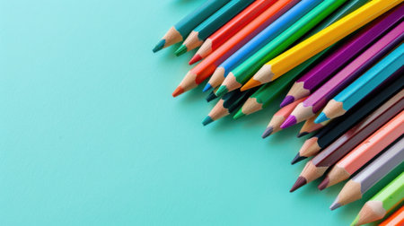 A vibrant assortment of sharpened colored pencils is beautifully arranged on a calming teal background, perfect for art projects and educational purposes.の素材