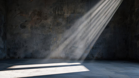 A dark and empty room features dramatic rays of light streaming through, illuminating the concrete walls and floor, creating an evocative atmosphere ideal for visual storytelling.の素材