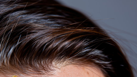This close-up image features shiny, healthy brown hair with subtle highlights, perfectly showcasing its texture and beauty against a neutral background. Ideal for beauty or haircare themes, this image captures the essence of modern elegance and grooming.の素材