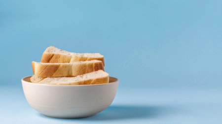 This image showcases freshly sliced white bread arranged neatly in a simple bowl against a light blue background, emphasizing the freshness and simplicity of the food.の素材
