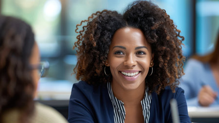 A cheerful woman in business attire smiles while engaging in a meaningful conversation in a modern office setting, showcasing warmth and professionalism.の素材