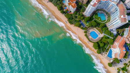 This stunning aerial image captures a beachfront resort with clear turquoise waters and pristine sandy beaches, surrounded by lush greenery and vibrant activity.の素材