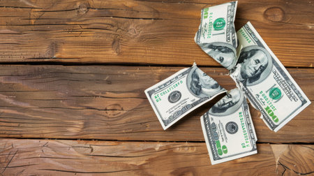 Crumpled hundred dollar bills are showcased on a rustic wooden background, symbolizing financial concepts, wealth, and economic themes in a modern business context.の素材