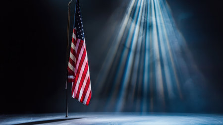 An American flag stands tall, illuminated by soft, dramatic rays of light, creating a poignant atmosphere that symbolizes freedom and patriotism.の素材
