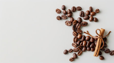 A visually appealing arrangement of roasted coffee beans and a cinnamon stick on a neutral background, perfect for culinary or cafe-themed projects.の素材