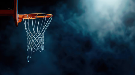 A striking image of a basketball hoop and net illuminated by dramatic lighting, set against a dark background. Perfect for sports, athletic themes, and creative concepts.の素材