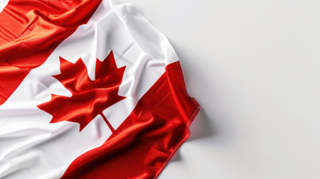 This image features the Canadian flag elegantly draped against a plain background, showcasing its vibrant red and white colors. The gentle folds create a soft, flowing appearance, perfect for themes of national pride and cultural identity.の素材