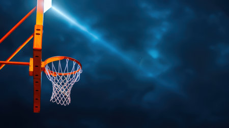 A striking view of an empty basketball hoop illuminated by a beam of light against a dramatic dark sky, evoking powerful emotions of competition and aspiration.の素材