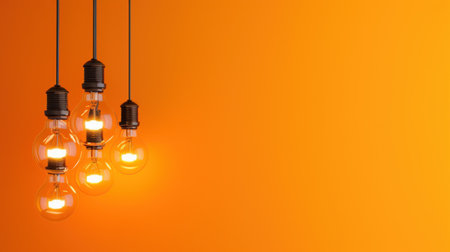 This image features beautifully arranged vintage light bulbs that emit a warm glow against a bright orange background, perfect for various creative projects.の素材