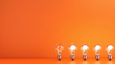 A series of light bulbs lined up against a bright orange background, creating a vibrant and modern feel, perfect for creative design applications.の素材
