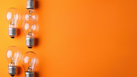 A captivating image featuring five light bulbs arranged on a vibrant orange background. The bright colors and clear glass create a lively and modern atmosphere, perfect for design and creative concepts.の素材