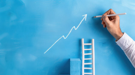 A creative representation of growth in business, featuring a hand drawing an upward arrow on a blue background with a ladder and blocks, symbolizing progress.の素材