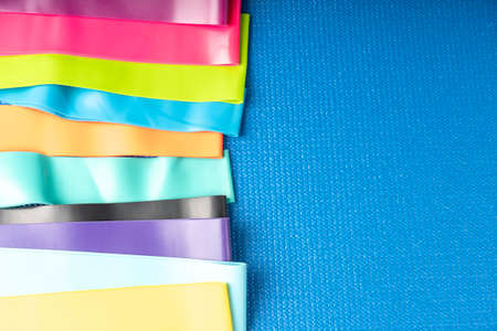A set of colorful elastic fitness band. Expanders for women and weight loss on a blue background Flat layer of various fitness bands, space for text Elastic elastic bands for fitness, selective focusの写真素材