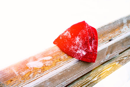 a mans hat is forgotten on a park bench in winterの写真素材