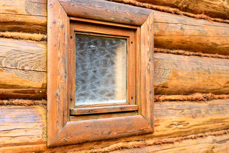 log wall, corner of a wooden house and a windowの写真素材