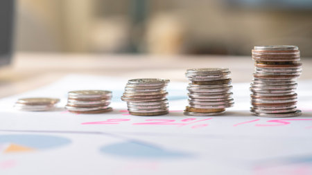 A stack of coins on a table with a graph showing the value of the coins. The coins are piled up in a pyramid shape, with the bottom row being the largest and the top row being the smallestの写真素材