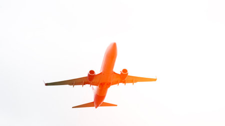 An orange airplane is flying through the sky. The image has a bright and energetic mood, as the...