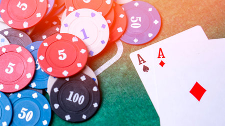 A pile of poker chips and a pair of playing cards on a green table. The chips are numbered from 1 to 50 and the cards are a pair of acesの写真素材
