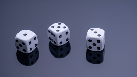 Three white dice are on a black background. The dice are arranged in a row, with the middle one slightly larger than the other two. Concept of anticipation and excitementの写真素材