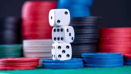 Three white dice are stacked on top of each other in front of a pile of red, blue, and green poker chipsの写真素材
