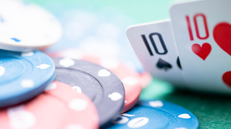 A poker player has a couple of tens, a good combination to continue playing and raise the stakes. Two cards at the poker table, the player looks at the hand against the background of playing chips. High quality photoの写真素材