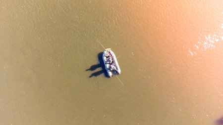 A raft with people in it is floating on a brownish water. The people are enjoying their time on the...