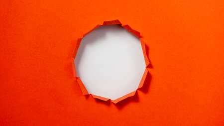 A red and white piece of paper with a hole in the center. The hole is large and circular, and the paper is cut in a way that it looks like it has been torn openの写真素材