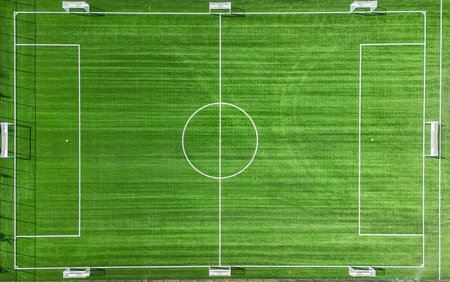 A soccer field with a white line in the middle. The field is green and empty