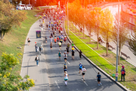 A group of runners on a city street, capturing the close-up views of their legs as they participate in the marathon, a man running on an asphalt road during an athletic event. High quality photoの写真素材