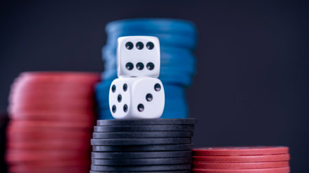 A pair of dice sits on top of a stack of poker chips. Concept of excitement and anticipation, as if someone is about to make a big bet or take a risk. The contrast between the white diceの写真素材