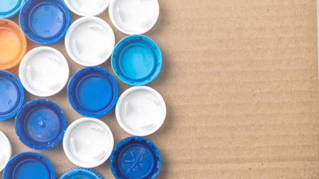 A collection of blue and white plastic caps are arranged in a pattern on a brown background. The caps are of different sizes and colors, creating a visually interesting and dynamic composition. High quality photoの写真素材