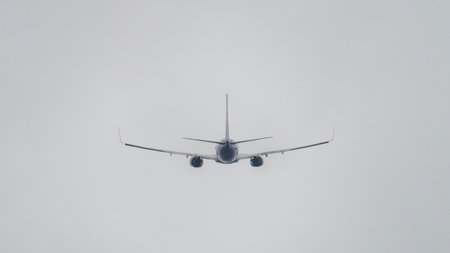 A large jet plane is flying through a cloudy sky. The plane is the main focus of the image, and it is soaring through the air with ease. The cloudy sky adds a sense of depthの写真素材