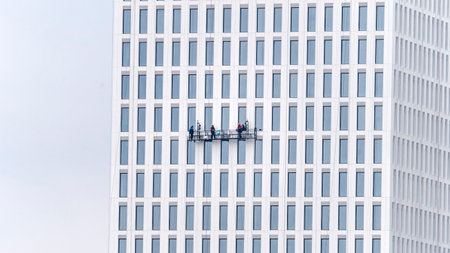 Window cleaners on a scaffold in a large commercial building are cleaning the facade of the building and repairing and washing the windows.の写真素材