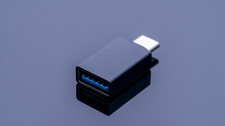 A small black USB cable with a blue connector. The cable is laying on a surface. The cable is not plugged into anythingの写真素材