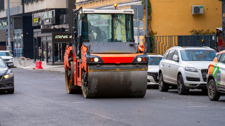Moscow, November 02 2025, A skating rink smooths out the fresh asphalt on a city street. This process makes the asphalt surface perfectly smooth. A heavy roller is used to press down the road surface in the city center. High quality photoのeditorial素材