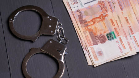 A pair of handcuffs and a stack of banknotes. The handcuffs are on a table next to the money