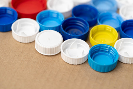 A row of plastic caps in various colors and sizes. The caps are arranged in a line on a brown surfaceの写真素材