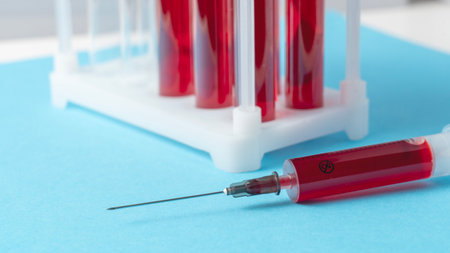 A close-up of human blood being drawn into a syringe, with several test tubes in the background. High quality photoの写真素材