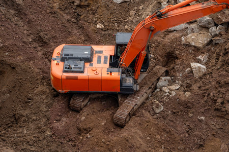 The excavator is shown in close-up from above. It is involved in the excavation of the ground for...