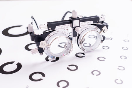 A pair of eyeglasses with a black frame and a white lens. The eyeglasses are placed on a white...
