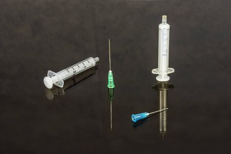 On the glass surface there are two syringes and needlesの写真素材