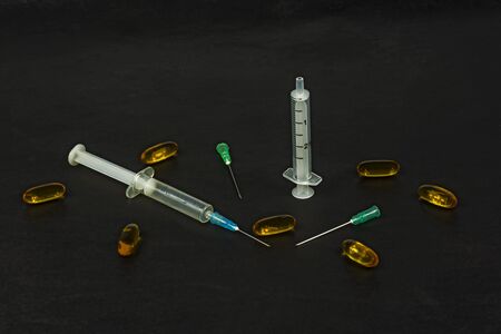 On a black background, there are syringes with needles and medical preparationsの写真素材