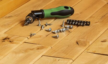 Mechanical screwdriver to tighten the screws on a wooden surface