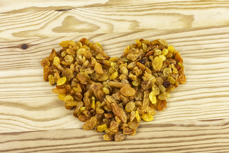On the wooden surface is a raisin laid out in the form of a heartの写真素材