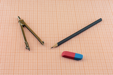 On a sheet of graph paper compass lie with pencil and eraserの写真素材