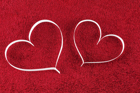 On the red surface are two paper heart silhouetteの写真素材