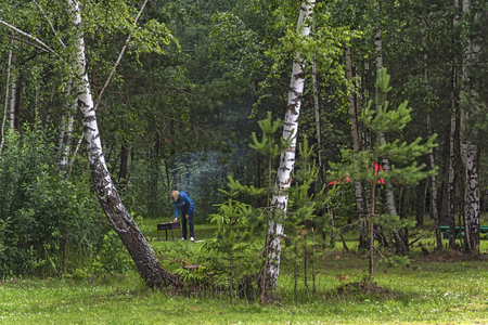 Summer vacation in the forest. The man is frying shish kebab on the grillの写真素材