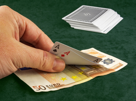 On the table lay banknote, and a man's hand lifts two cards at poker gameの写真素材