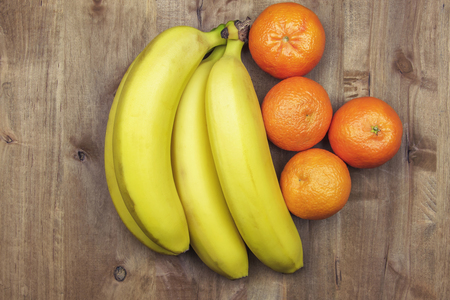 On a wooden surface lie bananas and tangerinesの写真素材